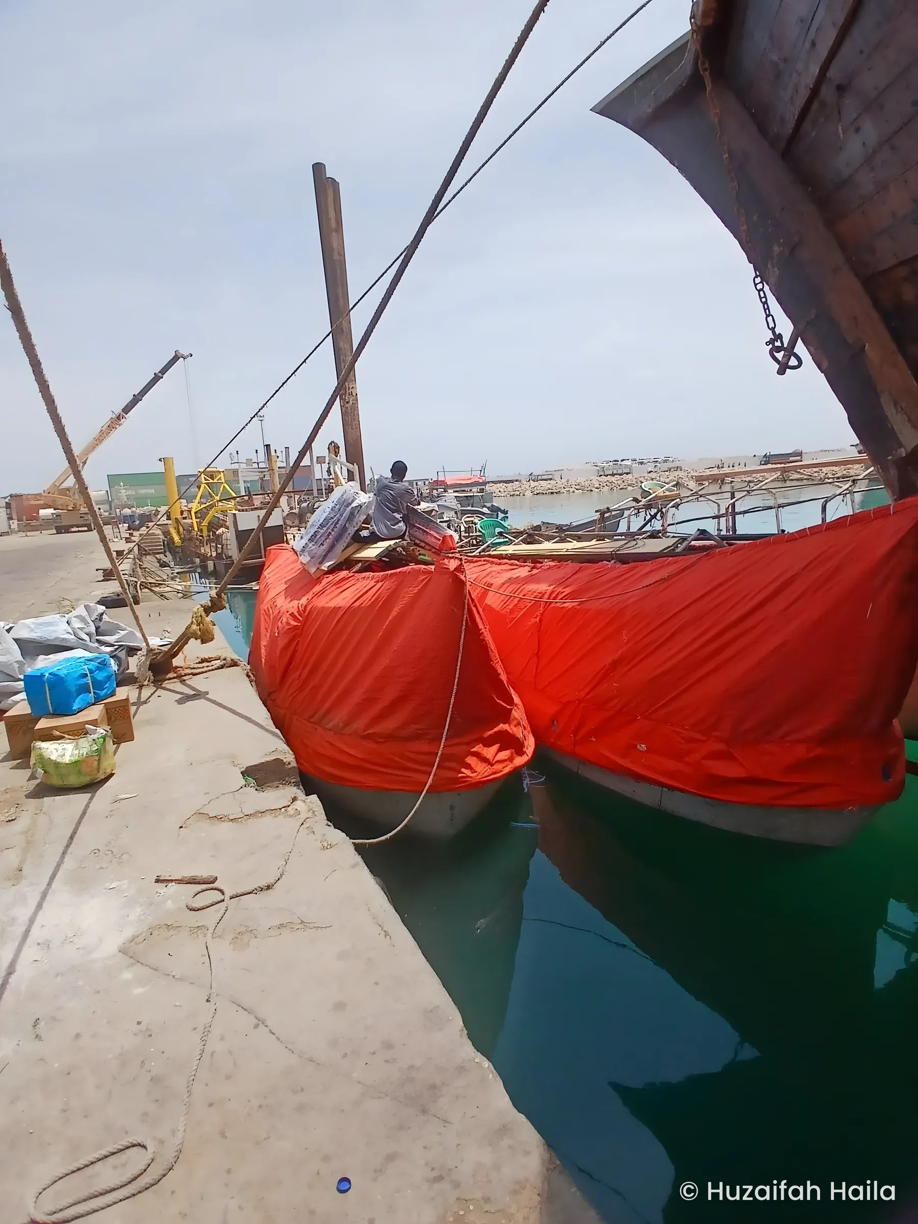 Dhows covered in red tarpaulin at quay, Bosaso Port, Somalia